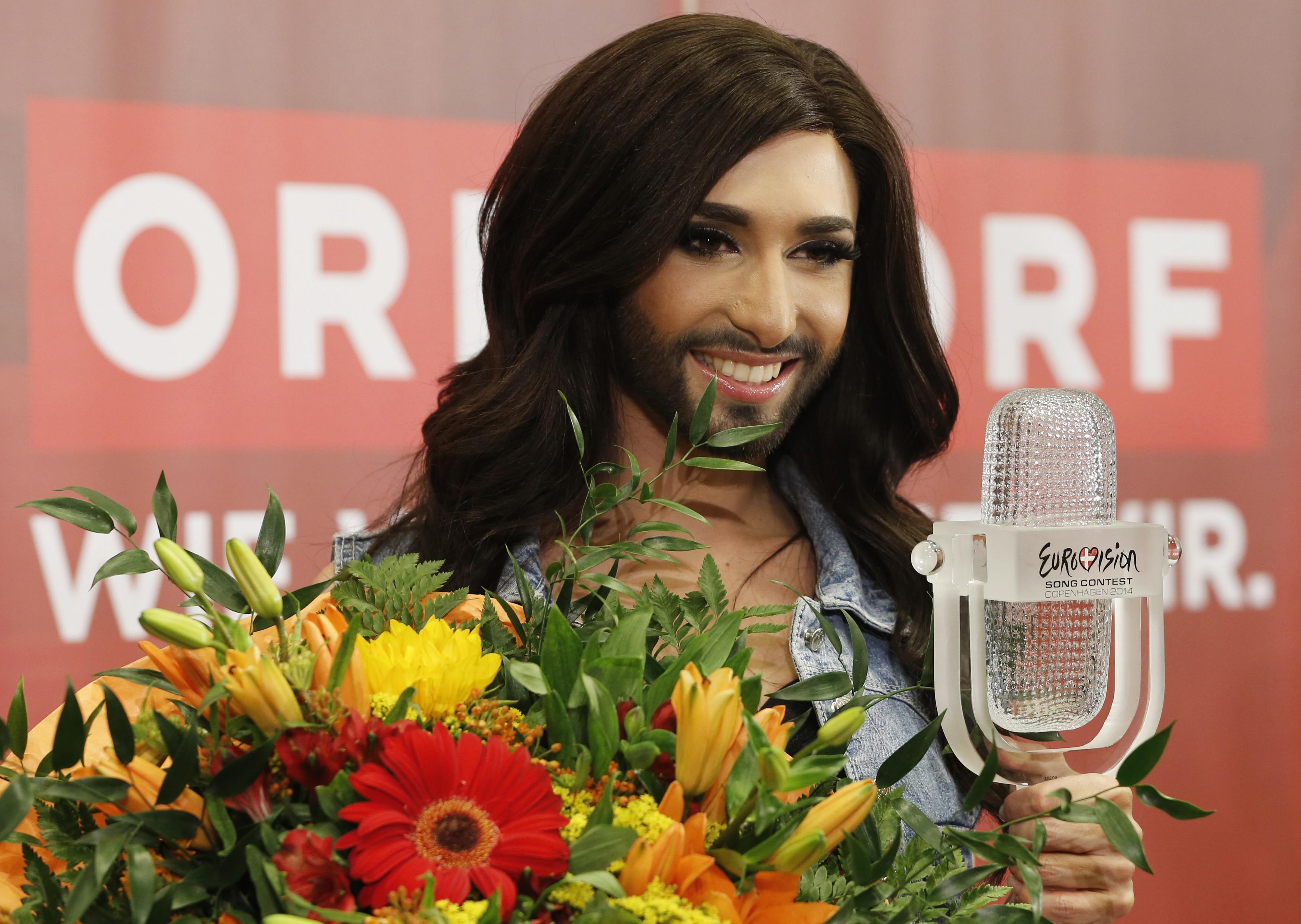 Austria's Conchita Wurst poses with her trophy and flowers after a news conference in Vienna
